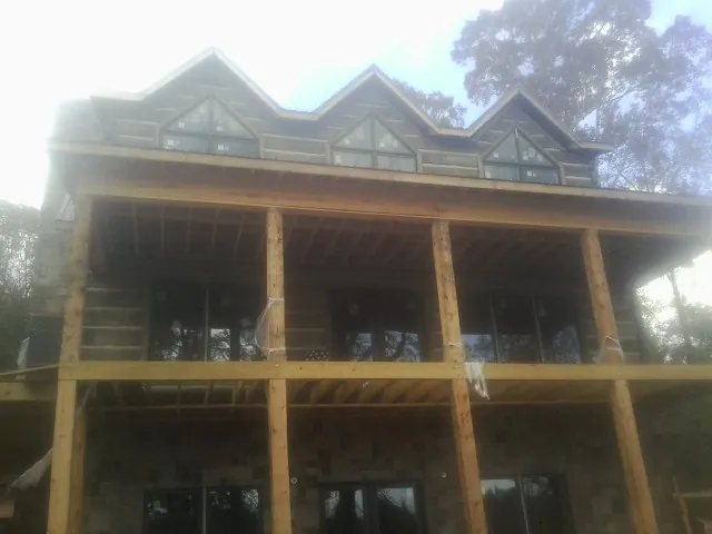 Dormers and porch framing on a large log home under construction — Roof Coating work by our crew in Burns